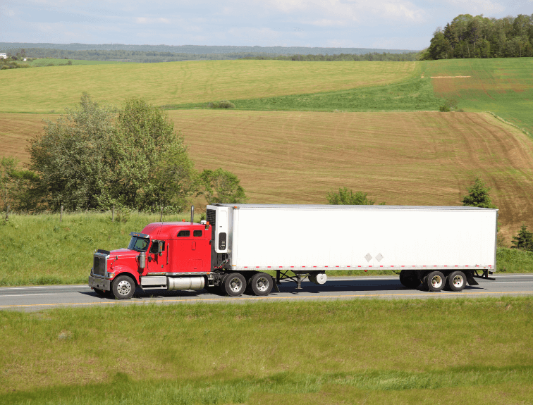 Image of semi truck driving on road in grassy hills.