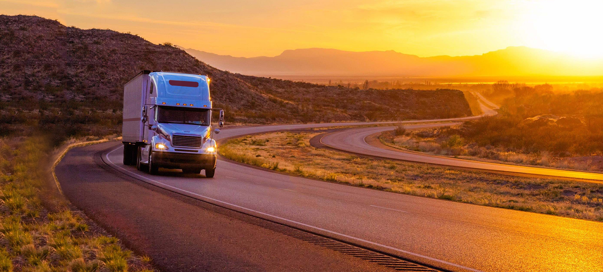 Image of semi driving with sunset in the background