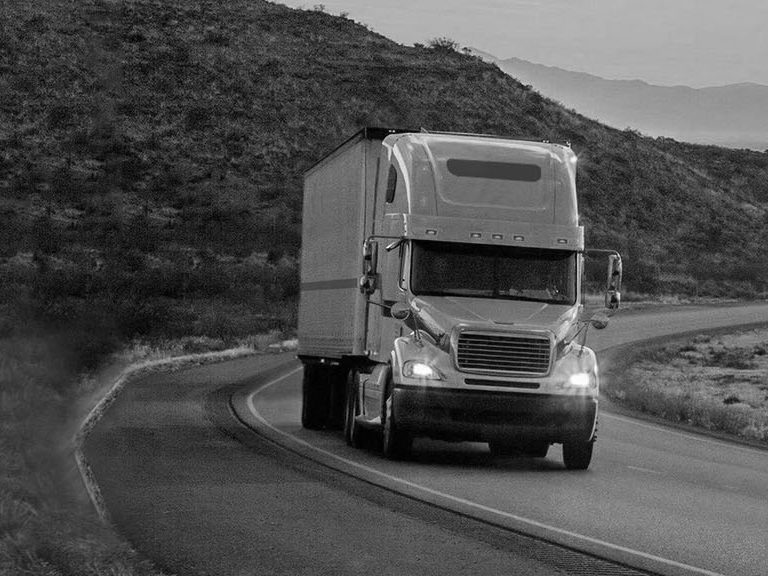 Image of a semi truck driving through mountains in black and white