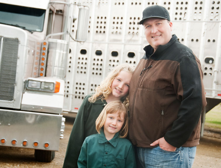 Image of man with two young girls standing in front of semi