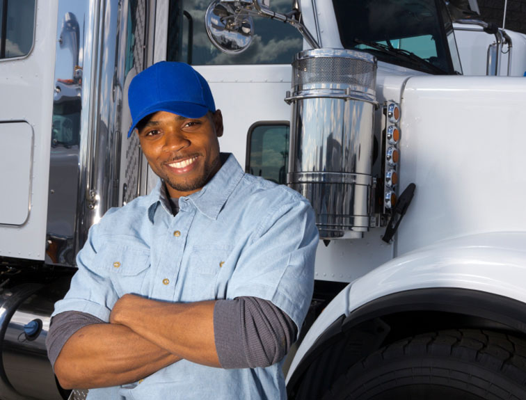 Image of smiling man with arms crossed in front of white semi